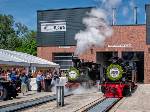 Der Moment der Eröffnung der neuen Werkstatt der RüBB und der Erlebniswelt im Bahnhof Putbus am 24. Mai 2024 mit den geladenen Gästen sowie den Loks I K Nr. 54 und 99 4652.