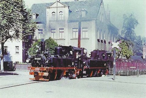 Die Aufnahme zeigt die Lokomotiven 99 605 und 99 573 mit einem GmP im Sommer 1954 beim Überqueren der Bahnhofsstraße zwischen Kirch­berg und Kirchberg Hp.