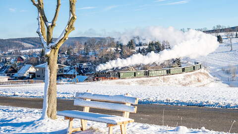 Die „Fotokurve“ am Hofweg in Cranzahl mit dem Bärenstein im Hintergrund hielt Hendrik Flath am 25. Dezember 2024 im Bild fest. An diesem ersten Weihnachtsfeiertag führte 99 1785-7 den Zug nach Oberwiesenthal.