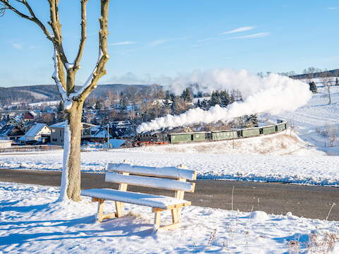 Die „Fotokurve“ am Hofweg in Cranzahl mit dem Bärenstein im Hintergrund hielt Hendrik Flath am 25. Dezember 2024 im Bild fest. An diesem ersten Weihnachtsfeiertag führte 99 1785-7 den Zug nach Oberwiesenthal.